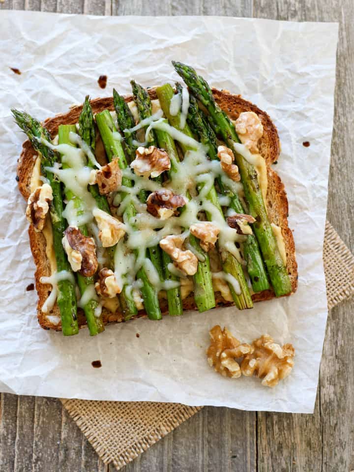 Overhead view of hummus and asparagus toast on a piece of parchment.