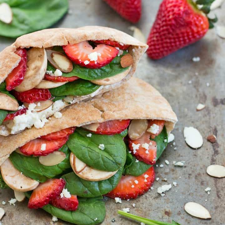 Sheet pan with stuffed pita pockets, strawberries, and spinach.