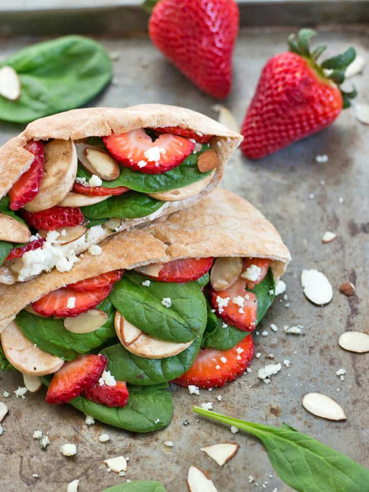 Stacked pita pocks on a sheet pan with strawberries and spinach.
