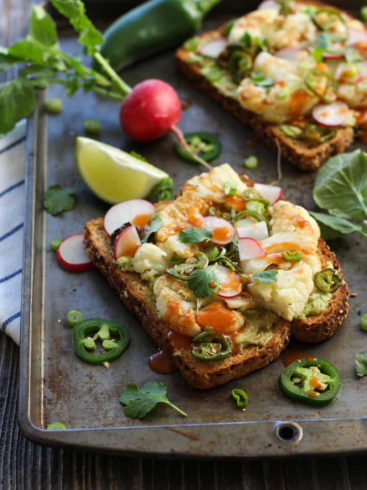 Avocado and cauliflower toasts topped with hot sauce and cilantro.