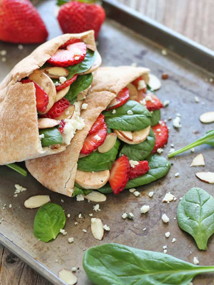 Strawberry and spinach stuffed pita pockets on a sheet pan.