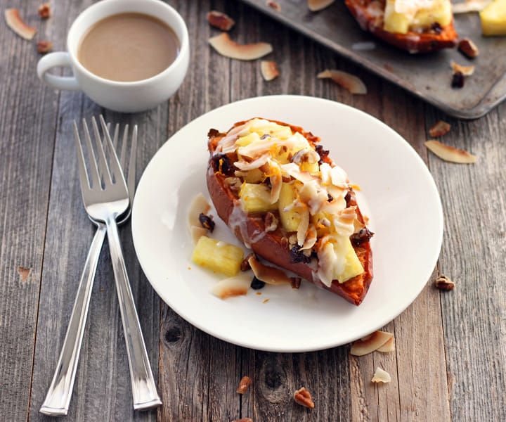 Wooden table with a baked sweet half on a plate next to a cup of coffee.