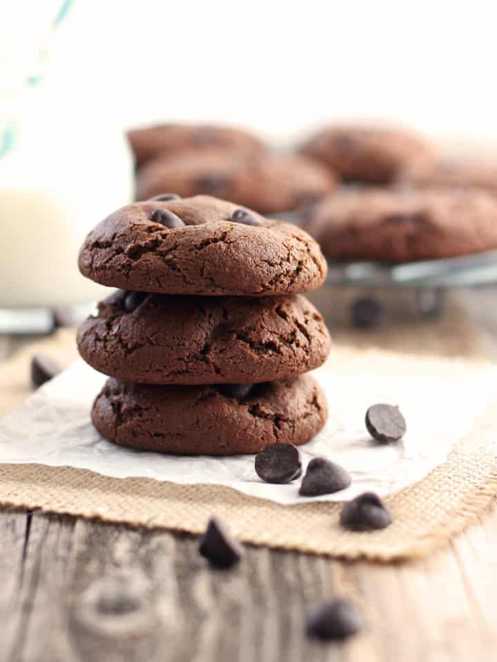 Small stack of chocolate cookies surrounded by chocolate chips.