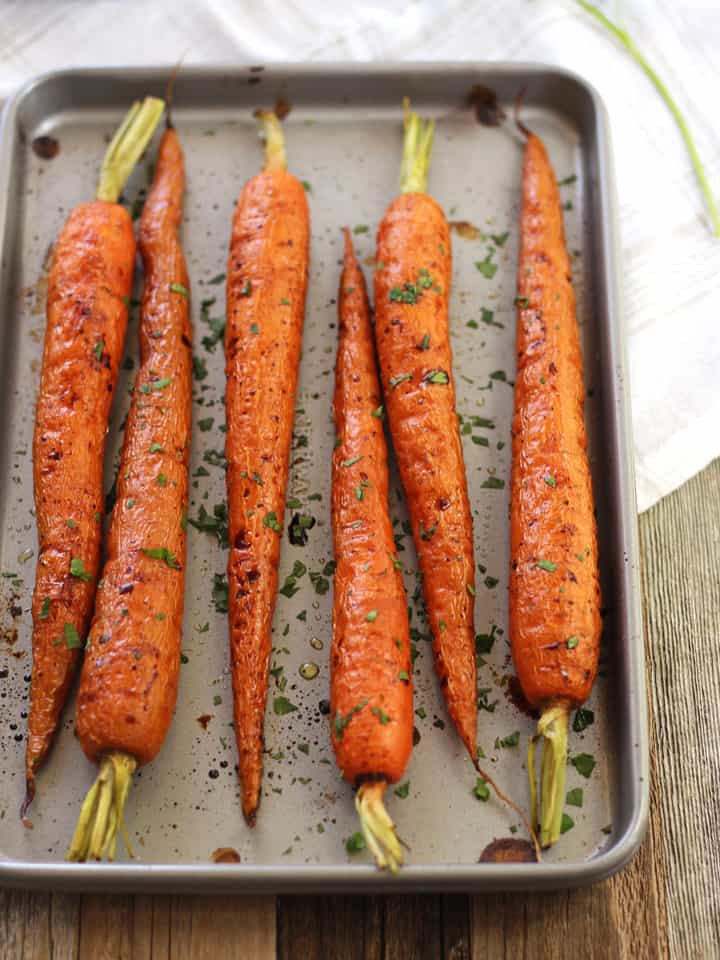 Closeup of whole roasted carrots topped with fresh parsley.