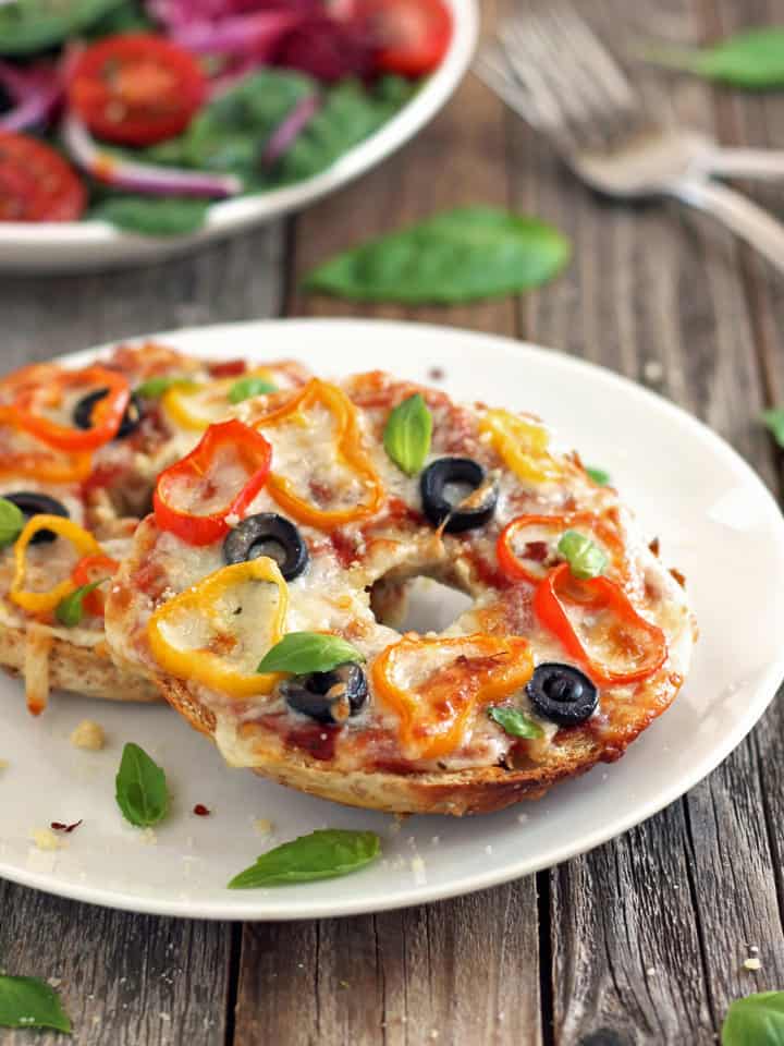 Two pizza bagels on a white plate.