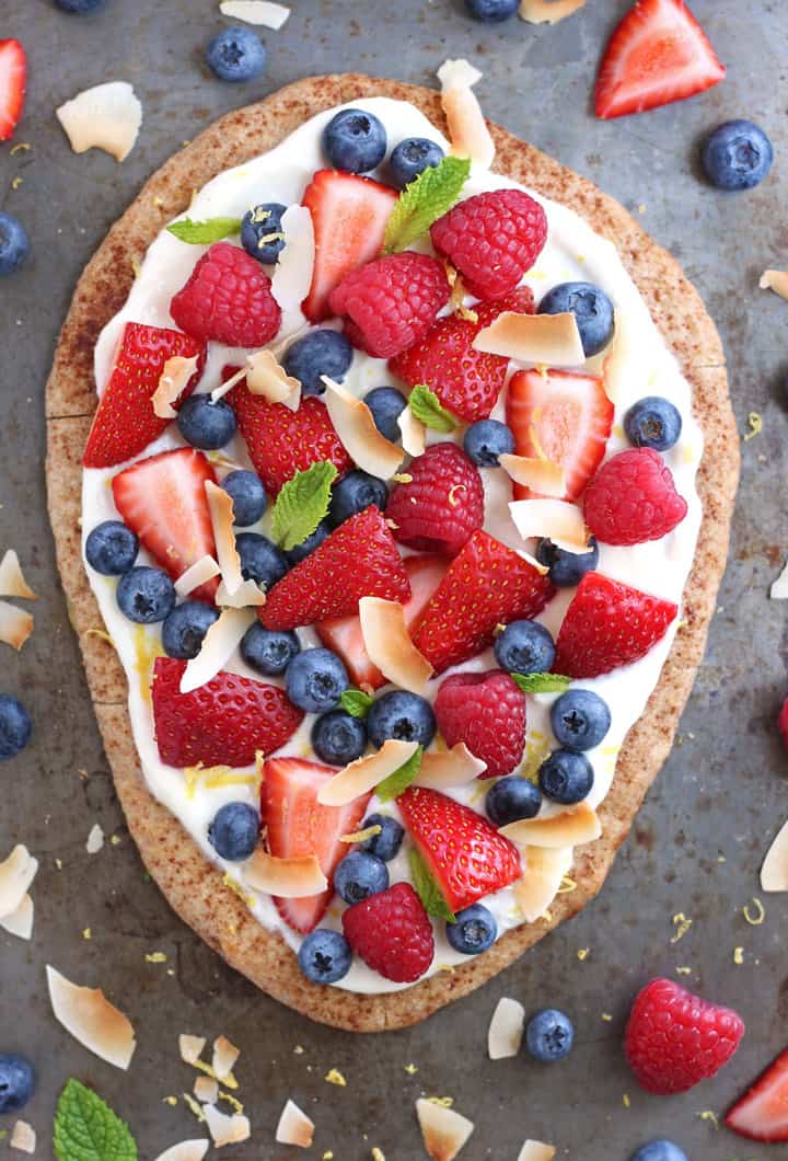 Overhead view of berries, coconut, and mint on a toasted flatbread.