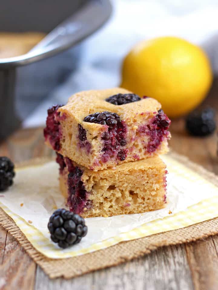 Little pancake squares on a piece of parchment next to fresh blackberries.