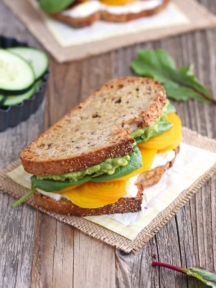 Golden beet and avocado sandwich on a piece of parchment.