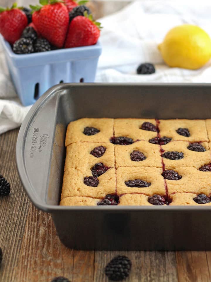 A square pan next to a blue basket filled with fresh berries.