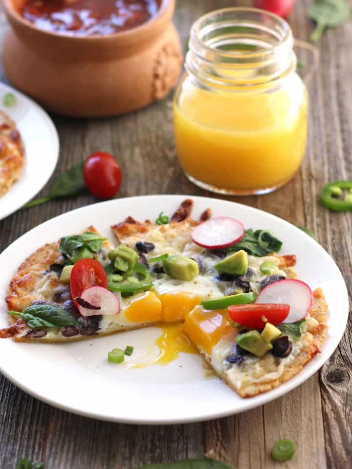 Egg tostada sliced with yolk running onto the plate.