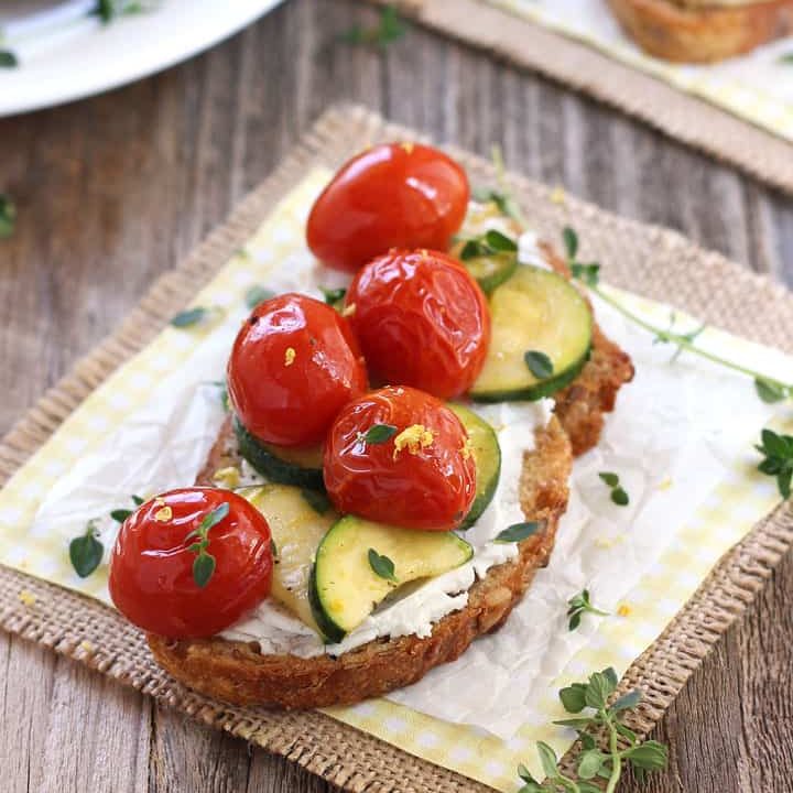 Toasted bread topped with cheese, zucchini, and cherry tomatoes.