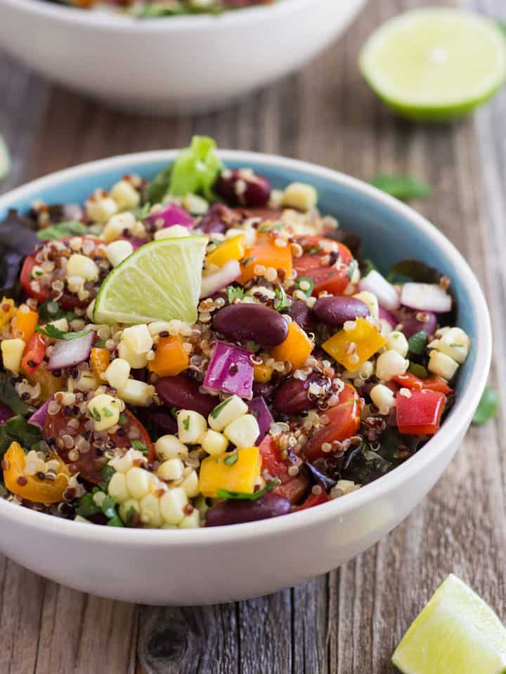 Close up of corn and quinoa salad topped with a lime wedge.