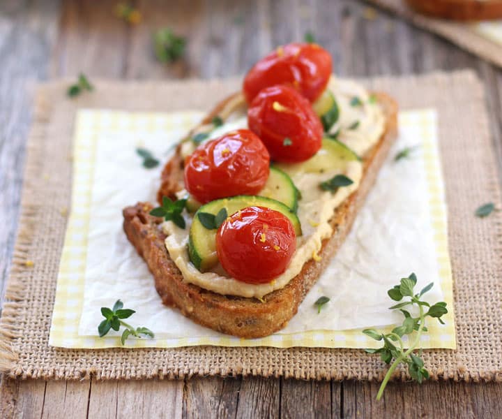 Hummus topped bread with juicy tomatoes and zucchini.