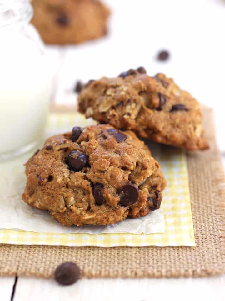 Oatmeal chocolate chip cookies next to a cold glass of milk.