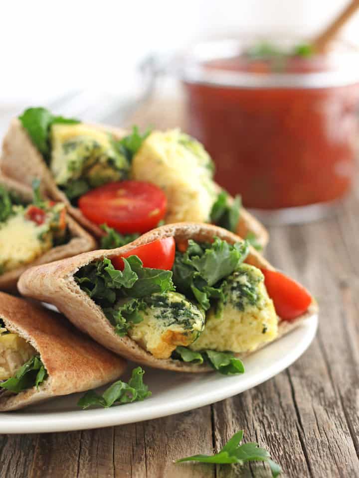 Egg Muffins chopped up inside a pita with kale and sliced cherry tomatoes.