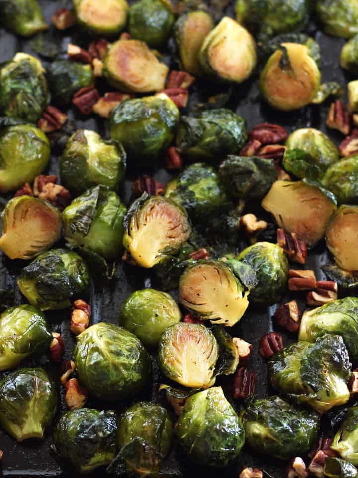 A pan of sticky sweet cooked Brussels sprouts with toasted pecans.