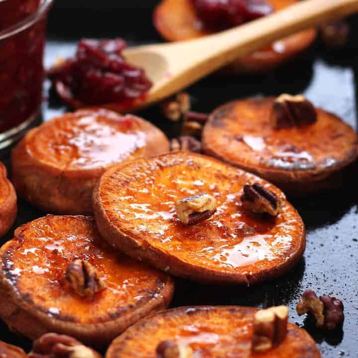 Close up of roasted sweet potato rounds topped with toasted pecans.