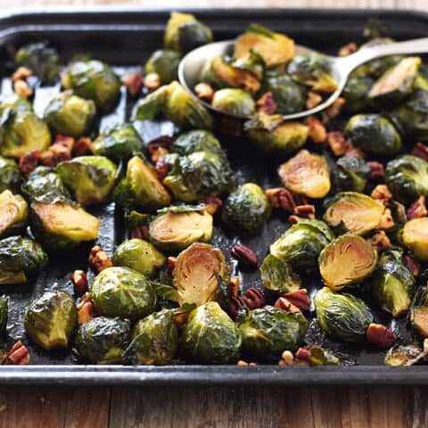 Small roasting pan of Brussels sprouts with a large serving spoon.