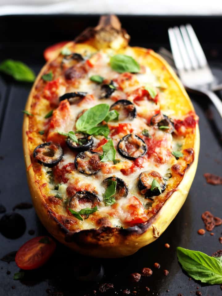 Stuffed spaghetti squash boat on a black sheet pan with a fork.