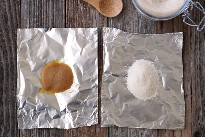 Piles of browned sugar and white sugar on pieces of foil.