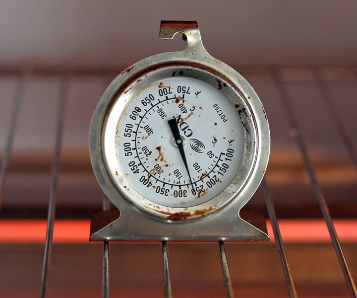 Closeup of oven thermometer on a cooking rack.