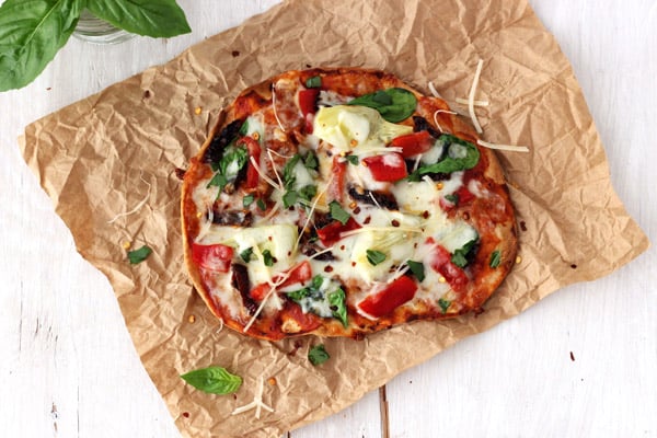 Overhead view of a baked tortilla pizza topped with fresh basil.