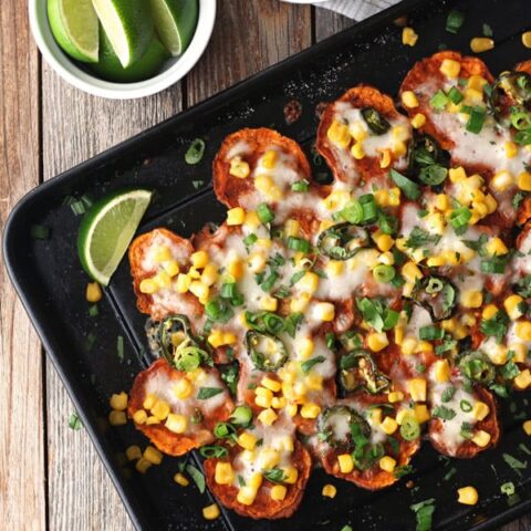 Overhead view of sweet potato nachos next to a bowl of lime wedges.