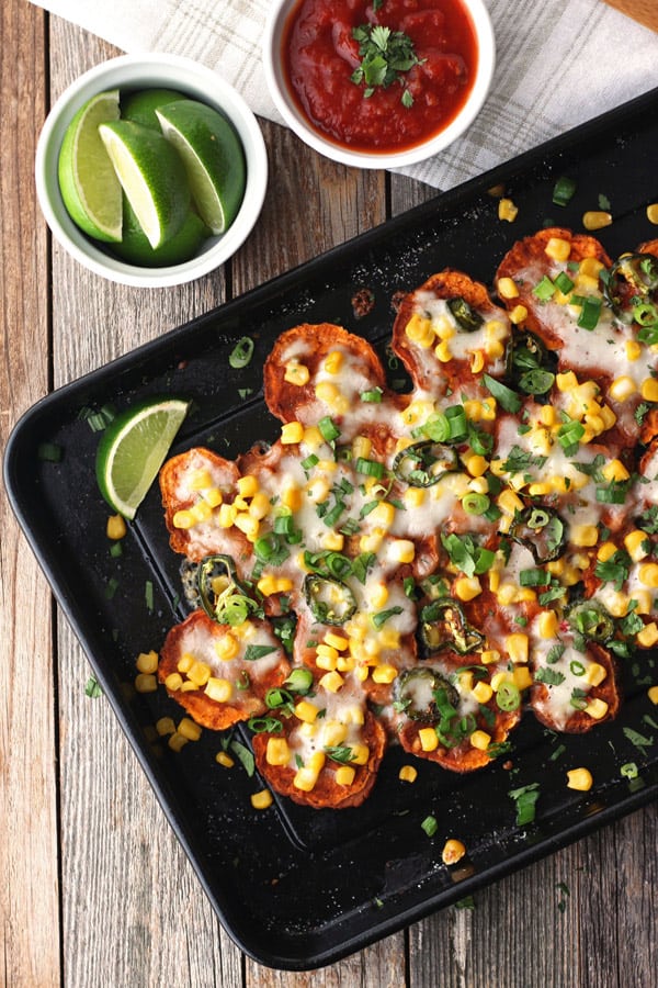 Overhead view of sweet potato nachos next to a bowl of lime wedges.