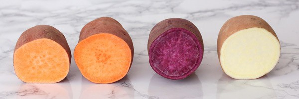 Sweet potatoes sliced open showing different varieties and colors