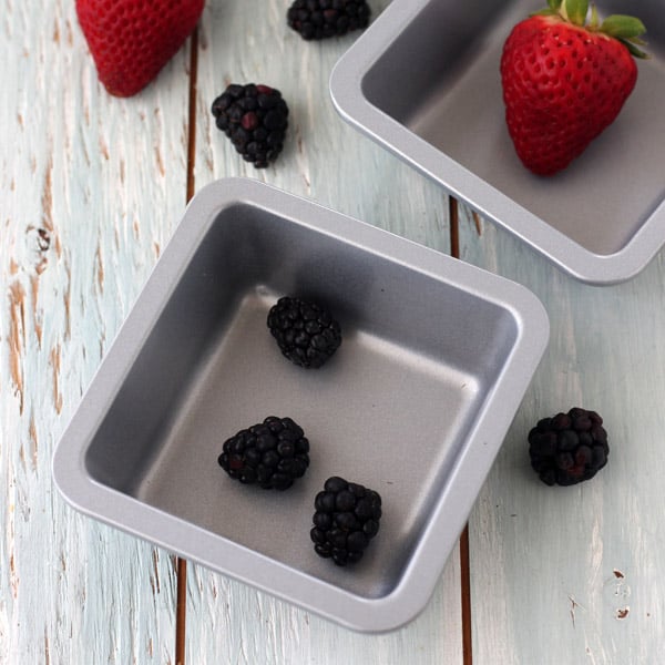 Mini metal baking pans with fresh berries.