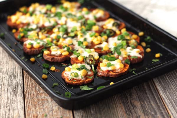 Topped sweet potato slices on a black baking sheet.