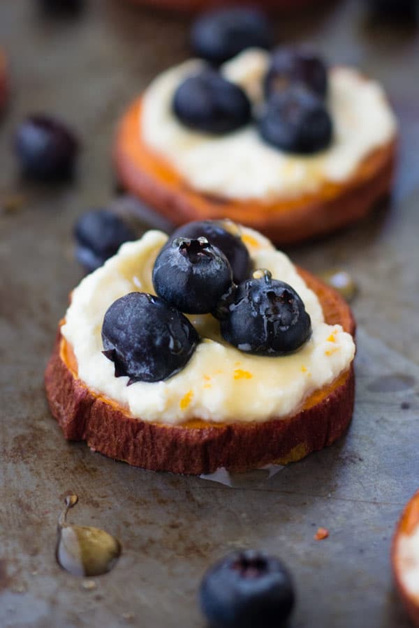 Closeup of sweet potato slice topped with ricotta and blueberries.