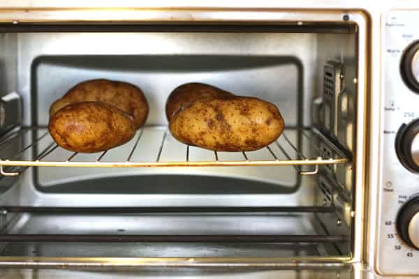 Potatoes baking on a rack inside of a toaster oven.