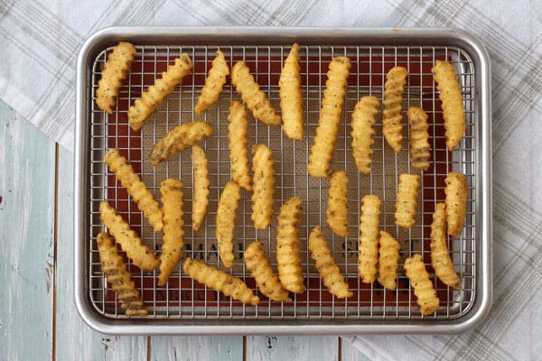 Overhead view of seasoned crinkle fries on a baking sheet. 