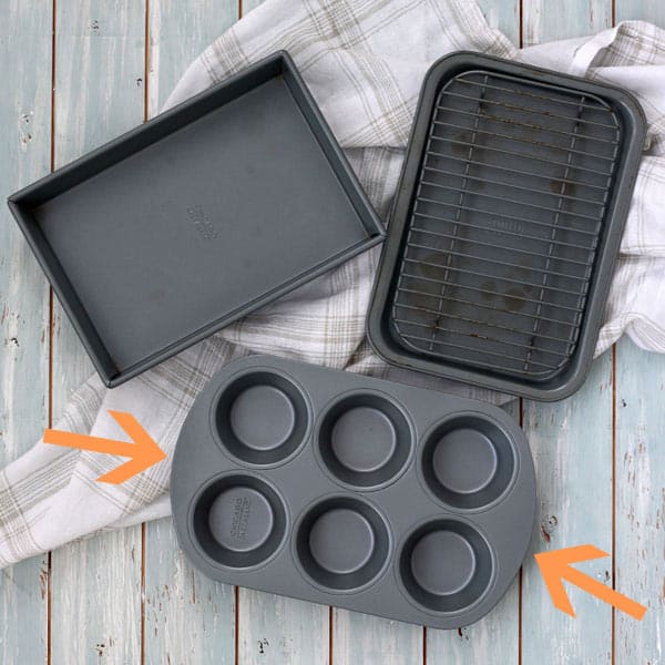 Toaster oven pan set with orange arrows pointing to the muffin tin edges.