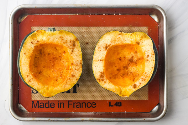 Oiled and seasoned squash halves on a quarter sheet pan.