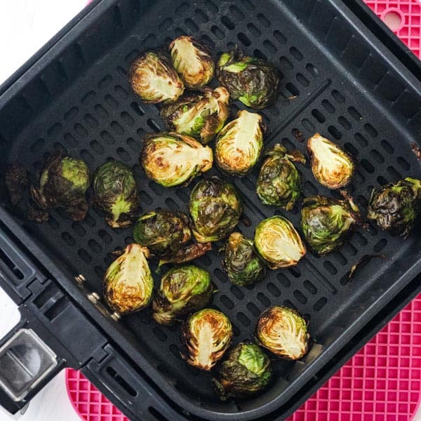 Overhead view of cooked Brussels sprouts in air fryer basket.