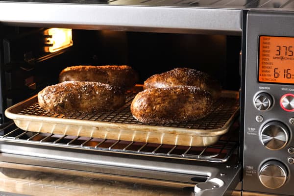 Baked potatoes cooking on a rack inside a toaster oven.