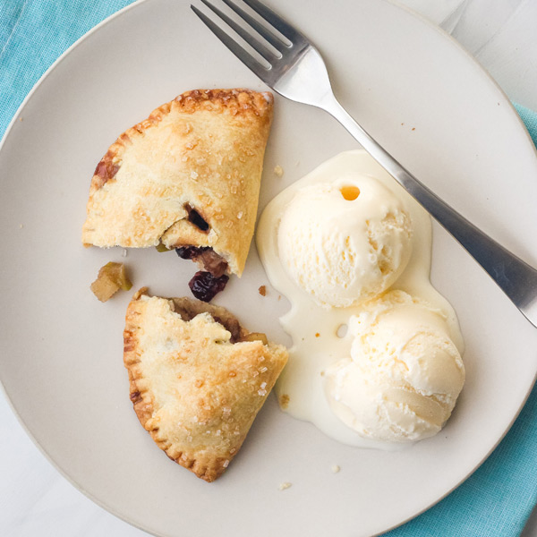 Overhead view of a baked hand pie broken in half next to two scoops of vanilla ice cream.