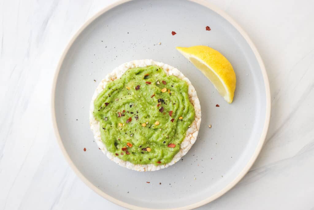 Rice cake topped with avocado and seasonings.