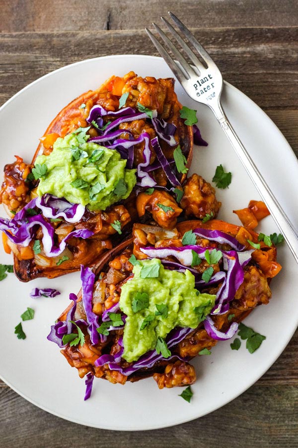 Tempeh stuffed sweet potatoes on a white plate.