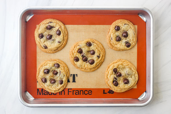 5 chocolate chip cookies on a silpat lined quarter sheet pan.