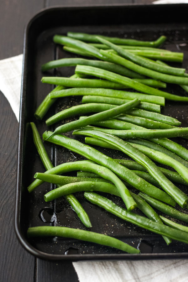 Fresh green beans on a dark toaster oven baking sheet.