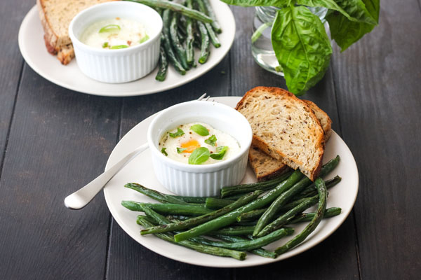 Dark wood table with fresh basil in a jar and white plates.