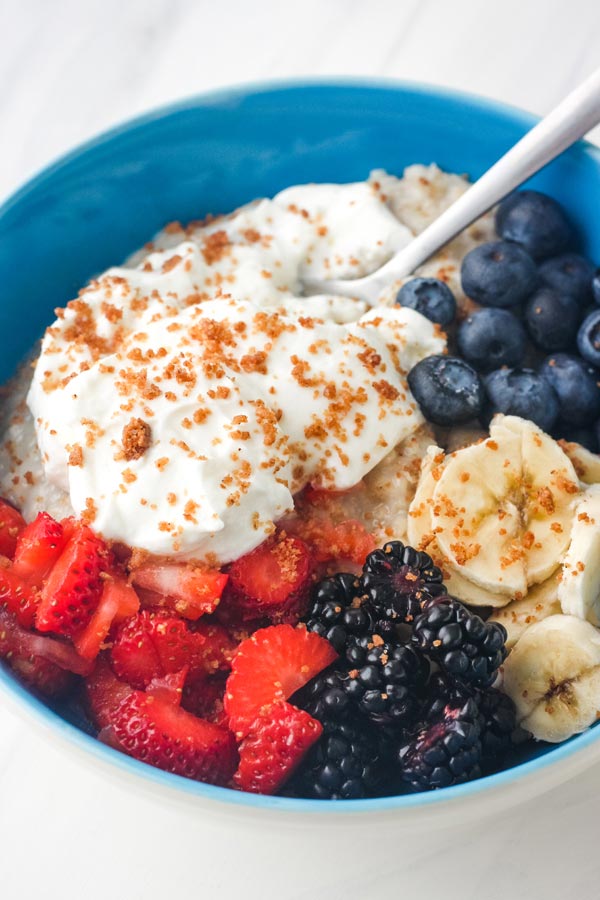 Bowl of oatmeal with berries, yogurt, and crumble topping.