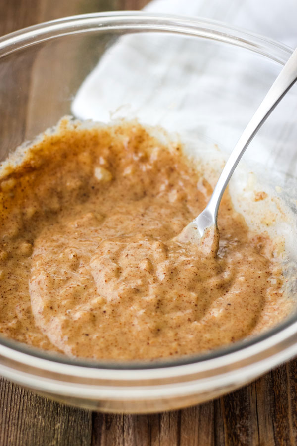 Mashed banana and almond butter in a glass bowl with a fork.