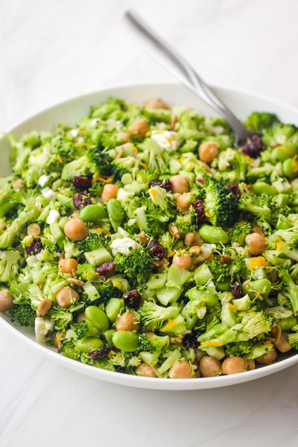 A large white bowl filled with broccoli salad and a serving spoon.