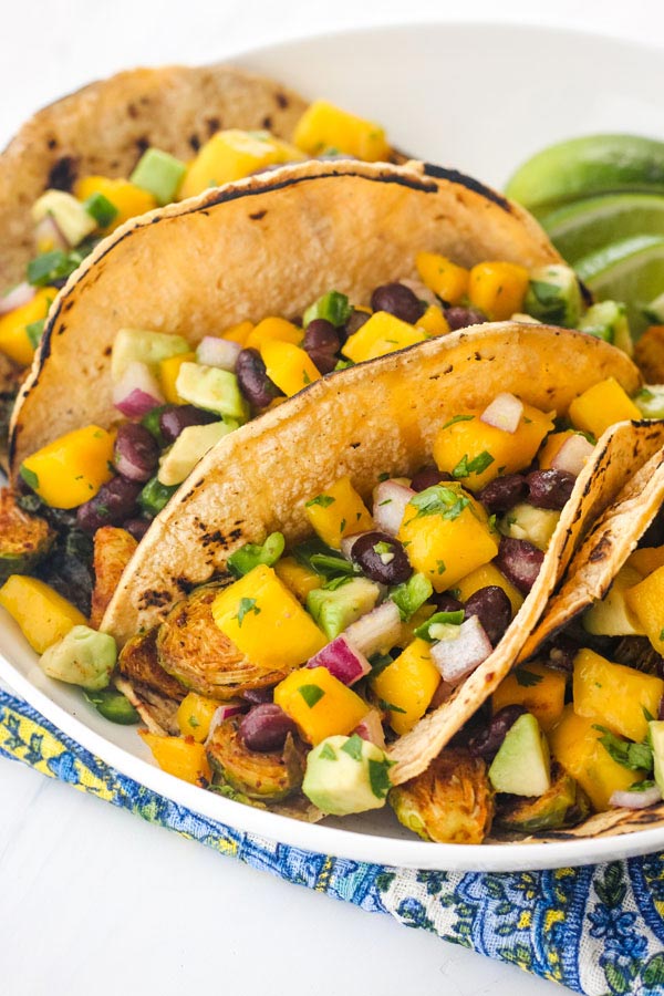 A white plate with veggie tacos on a blue napkin.