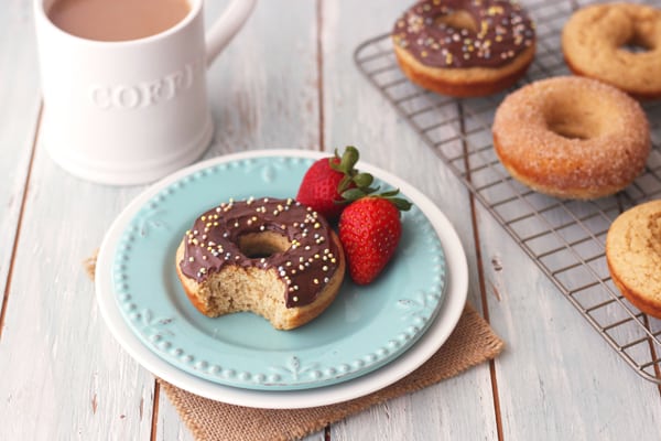 Nutella frosted baked buttermilk donut with sprinkles on a blue plate with strawberries.