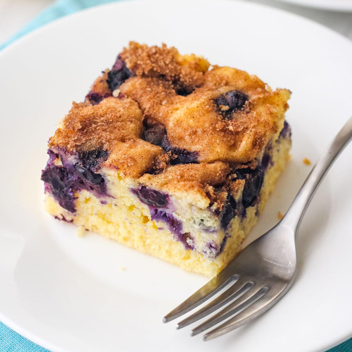 Close up of juicy blueberries on a piece of coffee cake on a plate.